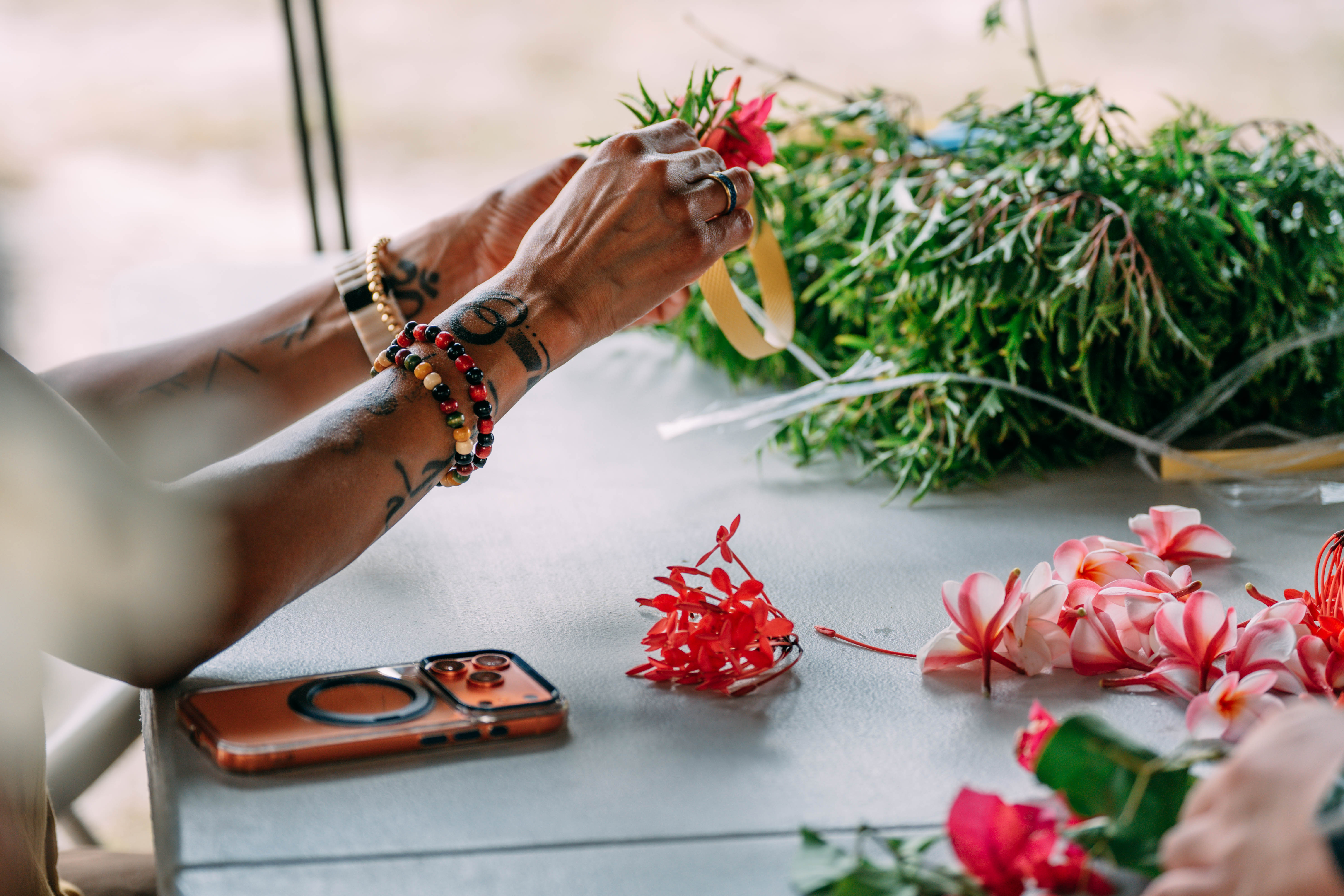 Hands preparing flowers and greenery for cultural adornment.